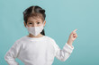 © DN6 - Asian little child girl wearing respirator mask to protect coronavirus outbreak and pointing hand to blank background, New virus Covid-19 from Wuhan China concept, Empty space isolated on blue