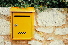 Beautiful Yellow Post Letter-box On The Stone Wall Outdoors.