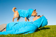 Dog standing on owner in matching blue hoody sweatshirts licking his face on bright green grass meadow
