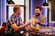 © F8  \ Suport Ukraine - Having a pint with friend. Two cheerful young men in shirt and tie toasting with beer while sitting together at the bar counter