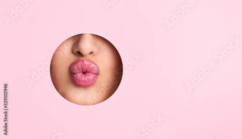 Photographie Woman showing red lips out of pink paper hole