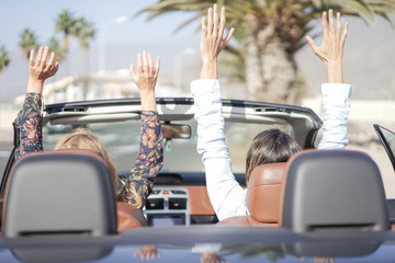 Couple enjoying a wonderful day. Young couple raising their arms in the car. Holiday and relationship concept - Image