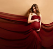 Pregnant woman with red flying fabric on brown background