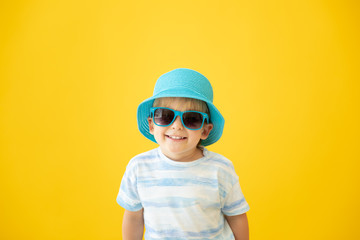 Wall Mural - Portrait of happy child against yellow background. Summer vacation concept