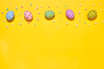 Wall Mural - Creative Easter holiday layout eggs colored handmade paint ed with ribbon foam party on yellow background.Seasonal flat lay concept.