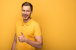 © LIGHTFIELD STUDIOS - happy handsome man in yellow outfit showing thumb up on yellow background