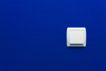 Light switch on blue wall background. Interior design. Minimal style.