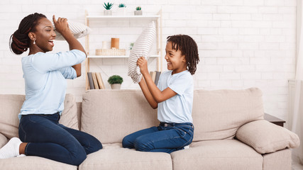 Wall Mural - Black mother and daughter having pillow fight