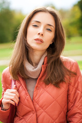 Wall Mural - Close up portrait of a young beautiful brunette girl in coral coat