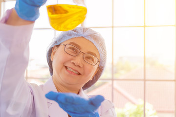 Poster - Discovering a cure for an Asian female scientist who is concentrated, holding a test tube and watching while working.