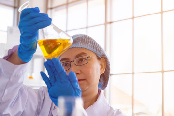 Poster - Discovering a cure for an Asian female scientist who is concentrated, holding a test tube and watching while working.