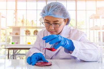 Poster - An Asian female scientist is researching a chemical formula in a lab.