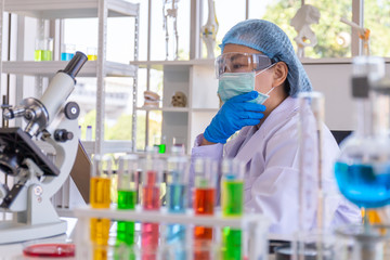 Poster - An Asian female scientist is researching a chemical formula in a lab.