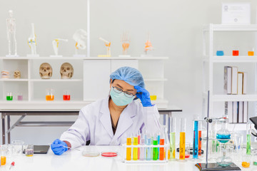 An Asian female scientist is researching a chemical formula in a lab.