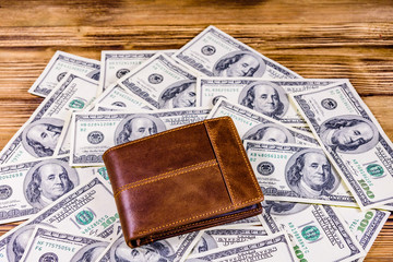 Closed brown leather wallet on the one hundred dollar banknotes