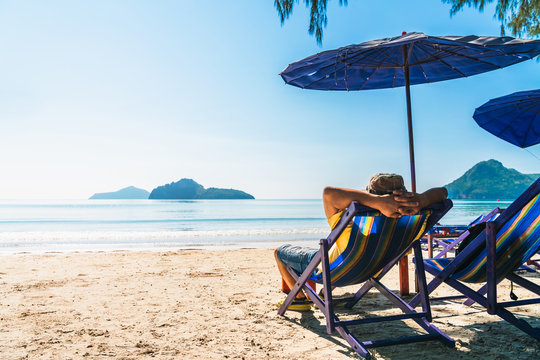 summer lifestyle asian man traveler relaxing on beach chair in front of vacation exotic beach, attra