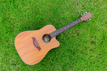 Acoustic guitar lays on grass field background