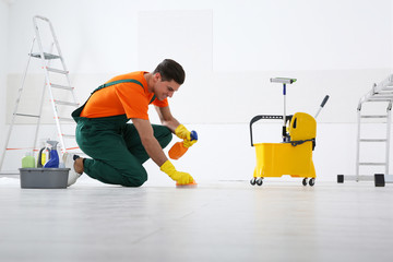 Wall Mural - Professional janitor cleaning floor with brush and detergent after renovation