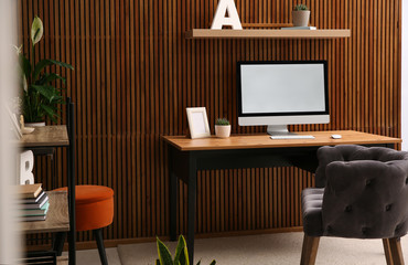 Poster - Comfortable workplace with computer near wooden wall in stylish room interior. Home office design