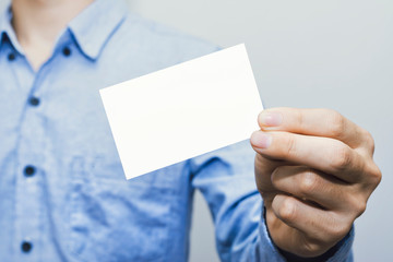 Man holding white business card on concrete wall background,mockup template