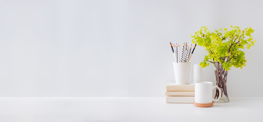 Home office, interior for bloggers workplace with branches with green leaves in a vases, office supplies