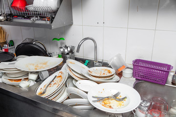 Metal sink full of dirty dishes, crockery, tableware