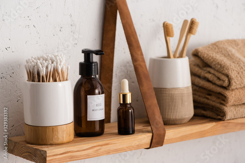 Fotografía Selective focus of hygiene and cosmetic products with towels on shelf in bathroo