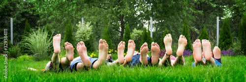 Fotografía Family relaxing on green grass, barefoot laying down and looking into the sky