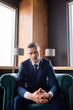 © LIGHTFIELD STUDIOS - businessman in suit with clenched hands sitting in armchair and looking at camera