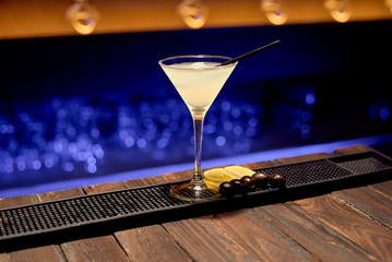 A dry martini cocktail with ice stands on a bar counter ready for serving to a customer.