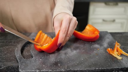 Wall Mural - housewife with red manicure cuts Bell pepper on black cutting board making salad for lunch extreme close view slow motion