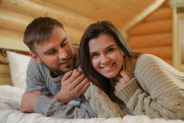 Sticker - Young couple wearing warm sweaters on bed at home