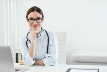 Portrait Of Young Female Doctor In White Coat At Workplace