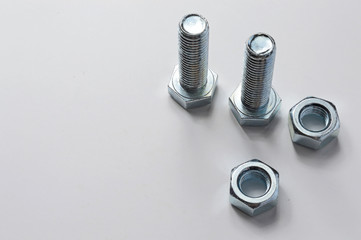 two bolts and nuts lying with them. White background.