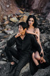 © Andrii - Asian couple in love hugs sitting on the rocks. Love story