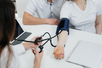 The doctor measures the pressure of a pregnant girl in the clinic. Pregnancy, and health care