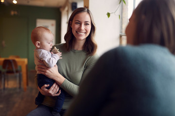 a beatyful mom is sitting on a cafe with her baby