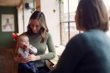 A beatyful mom is sitting on a cafe with her baby