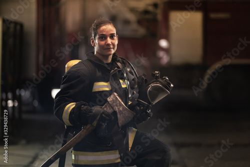Fototapeta female firefighter portrait wearing full equipment, oxygen mask, and an axe