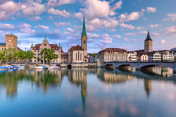 Wall Mural - Famous Fraumunster and St Peter church with reflections in river Limmat at sunrise in Old Town of Zurich, the largest city in Switzerland