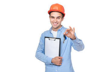 Smiling builder in helmet shows keys, isolated background, copy space