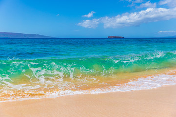 Beautiful view of small waves crashing in Makena Beach (Big Beach) on Maui, Haiwaii with Molokini Crater at distance