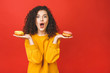 © denis_vermenko - Close up portrait of a satisfied pretty young girl eating donuts isolated over red background.