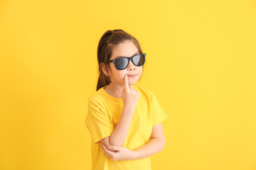 Wall Mural - Funny little girl with sunglasses on color background