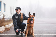 Female Police Officer With Dog Patrolling City Street