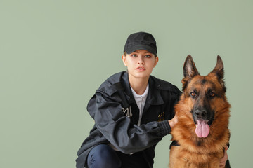 Female police officer with dog on color background