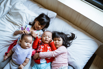 four children lie in bed hugging each other while looking at the camera