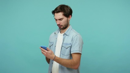 Mobile communication. Bearded guy looking with amazement at message on cell phone, chatting reading blogs and suddenly finding shocking information, surprised by news. indoor studio shot, isolated