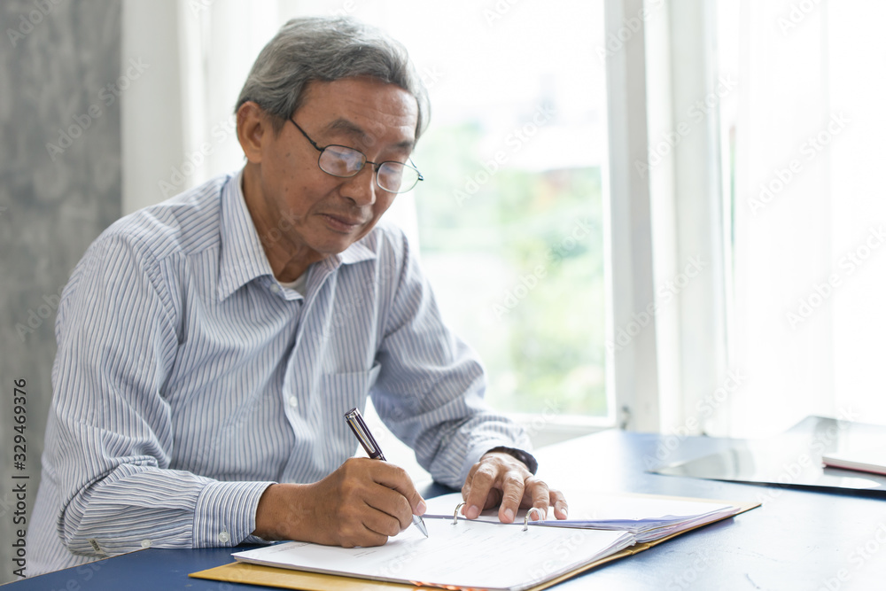 Asian smart business elder writing document report in the office. - obrazy, fototapety, plakaty 