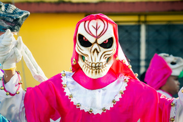 Wall Mural - closeup man in scary mask and costume poses for photo on dominican city street